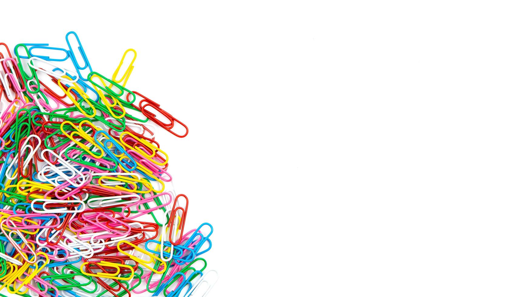 Many colorful stationery paper clips on a white background photo