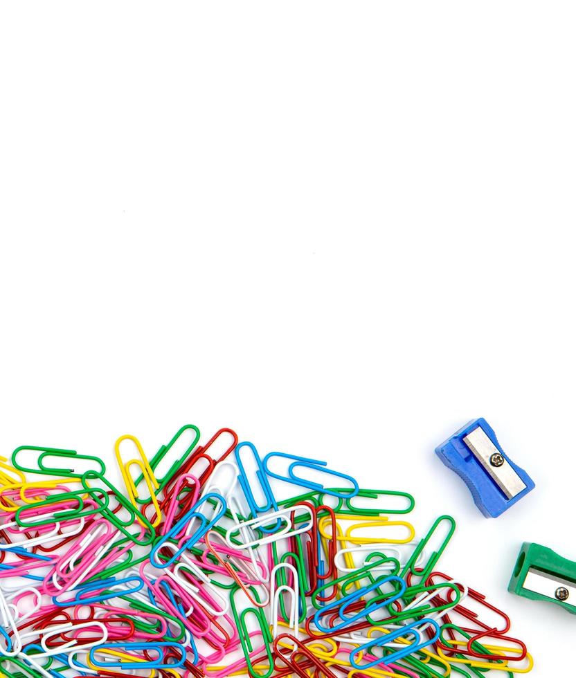 A lot of colored paper clips and pencil sharpeners on a white background photo