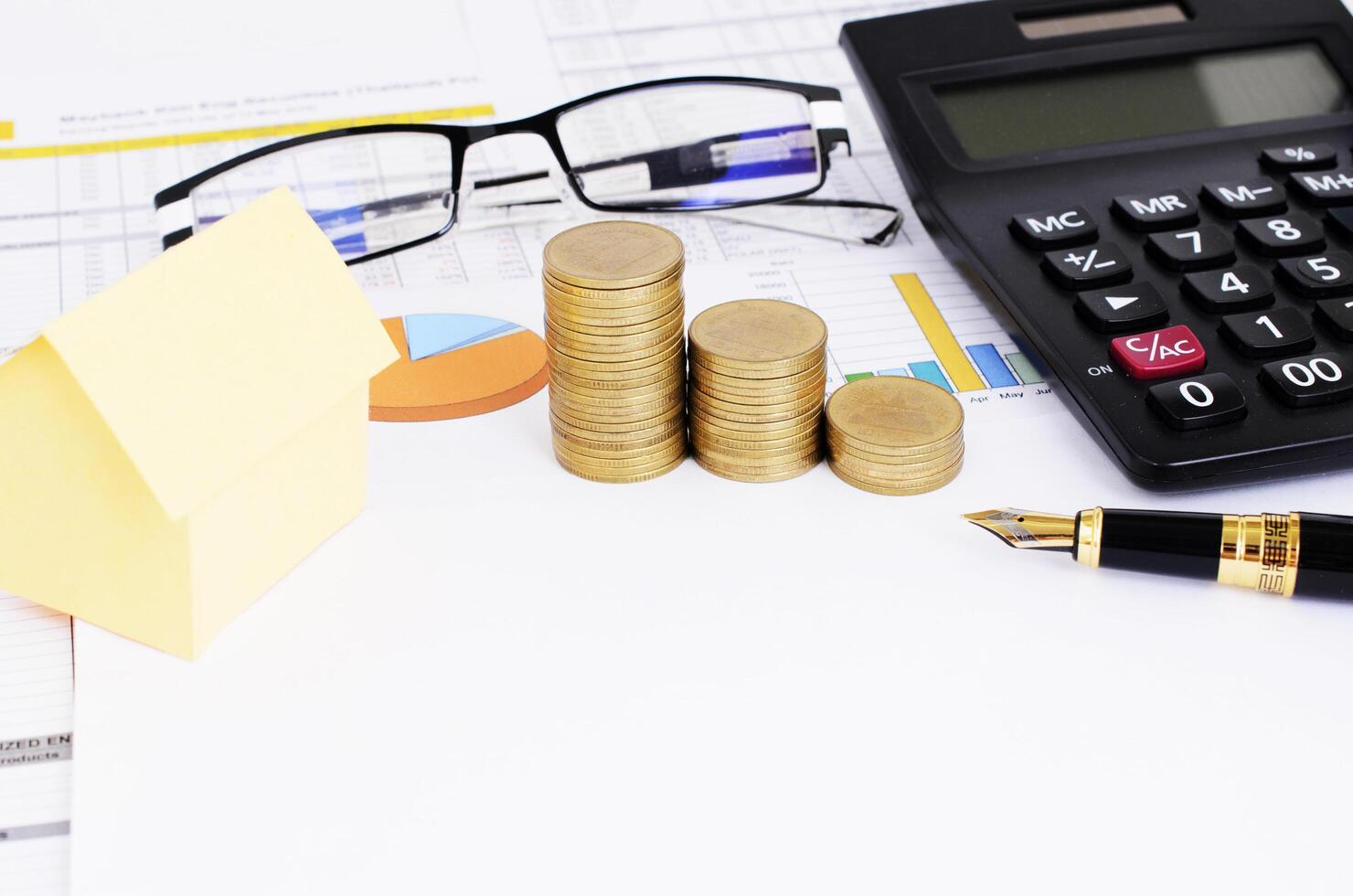 Mortgaget loans concept with fountain pen and coins stack and yellow hose paper and eyeglasses photo