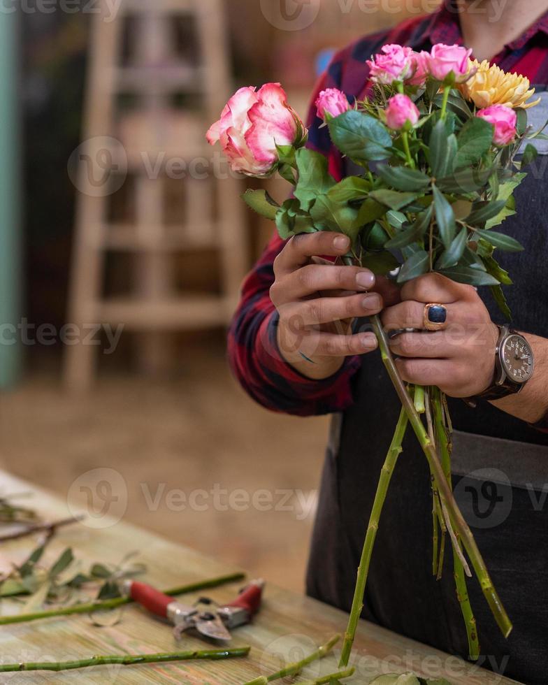 Hombre de floristería haciendo ramo de flores en la tienda foto