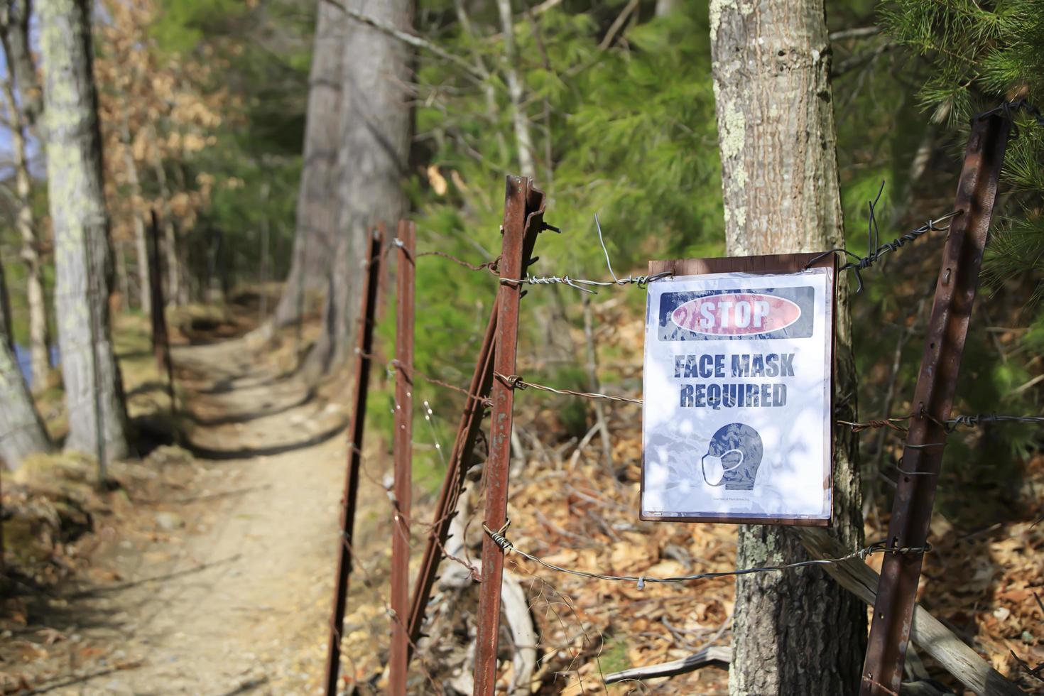 Face masks required sign on the side of a hiking path photo