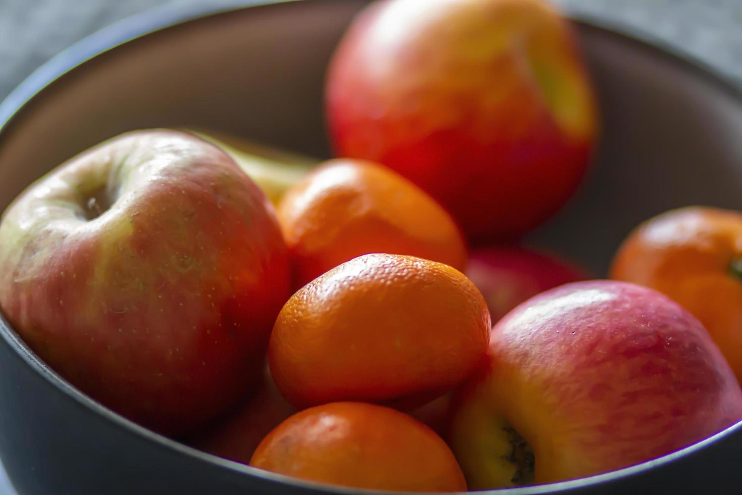 Tazón de naranjas y manzanas orgánicas frescas sobre una mesa foto