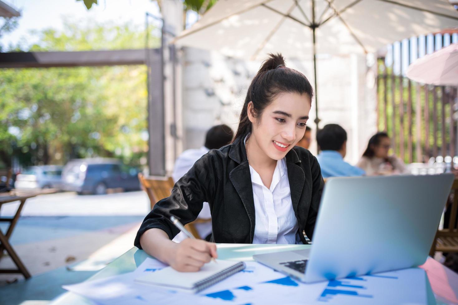 Ocupada joven empresaria trabajando en un escritorio con un portátil en una cafetería. foto