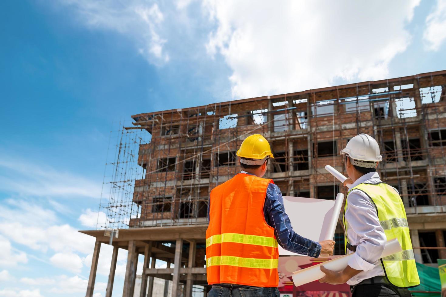 Businessman and engineer looking at a building blueprint at a high rise building construction site photo