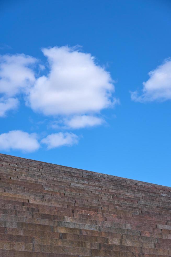 Granite steps against the blue sky with clouds photo