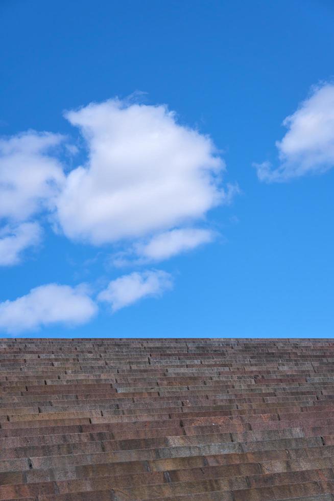 Granite steps against the blue sky with clouds photo