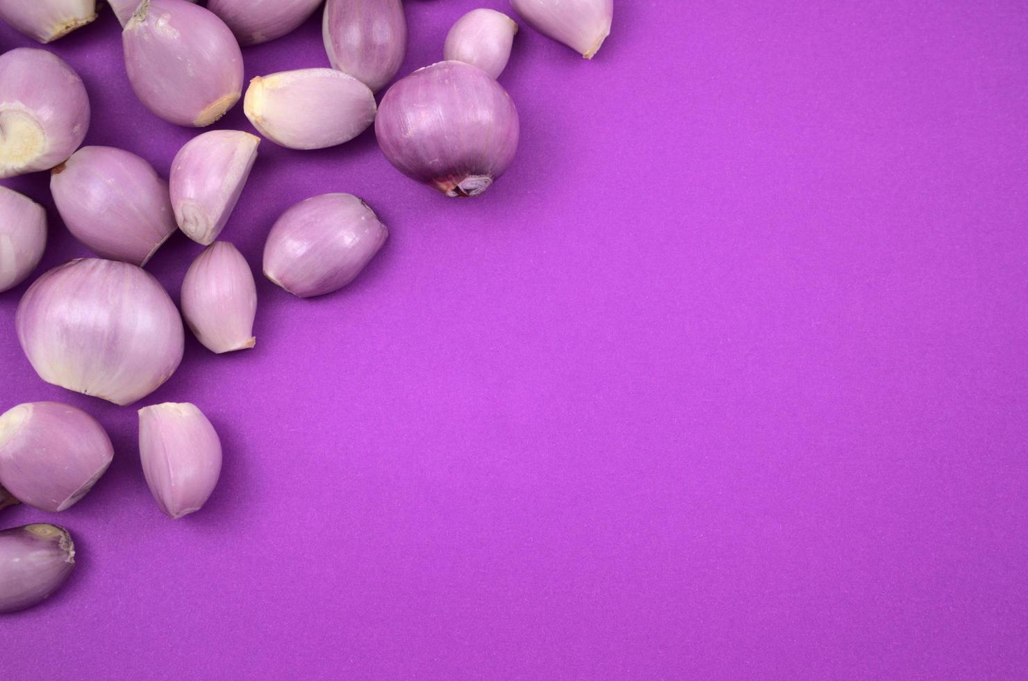 Cebollas frescas peladas planas yacen sobre fondo morado foto