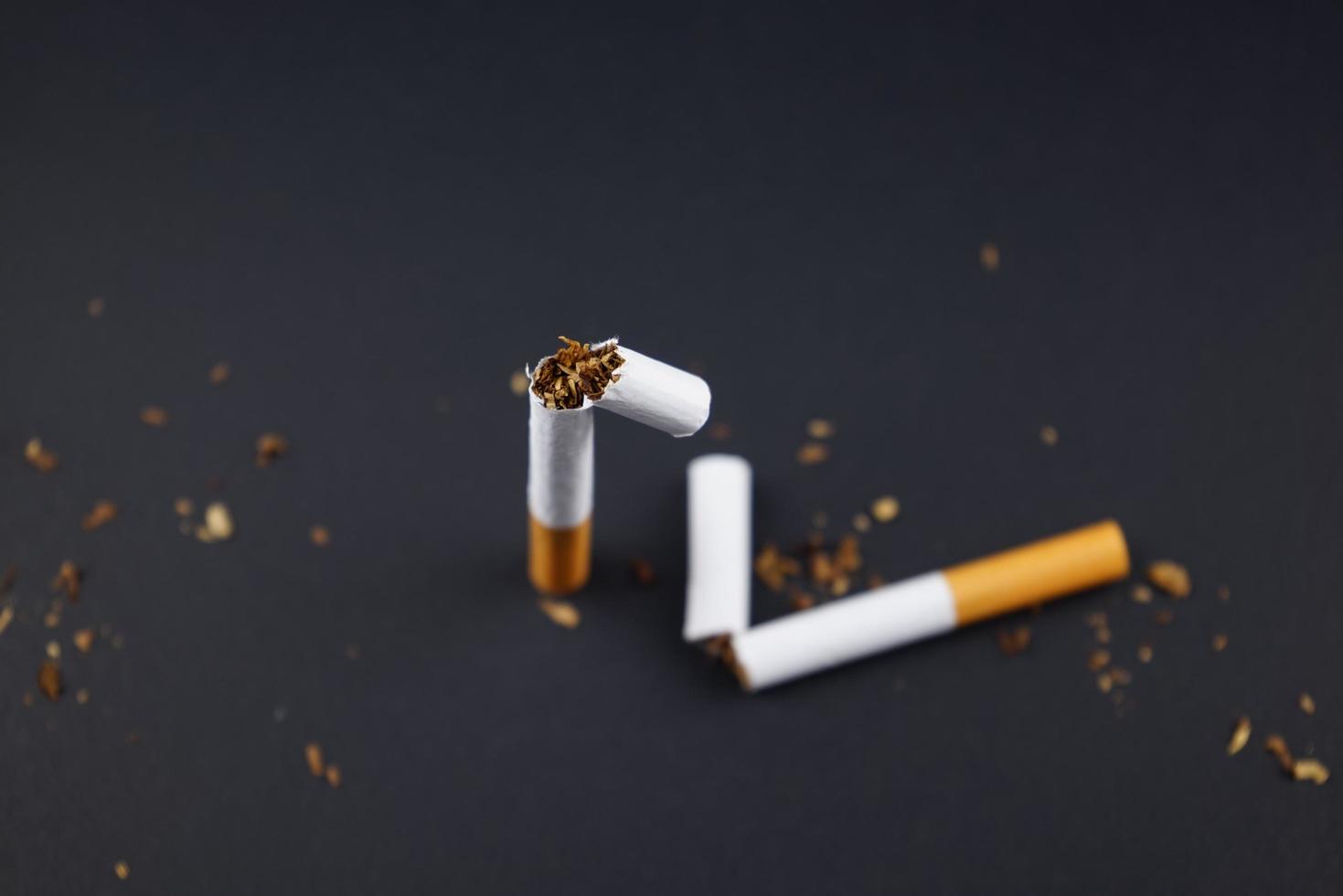 Breaking destroying cigarettes smoking tobacco flat lay on black grunge texture background for any smoking concepts like World No Tobacco Day or WNTD on 31 May or the dangers of using tobacco ideas photo