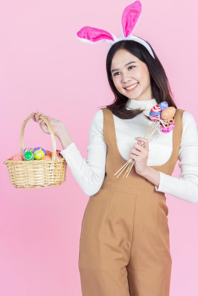 Retrato de una hermosa niña asiática con un huevo de pascua en un espacio de copia de fondo rosa foto