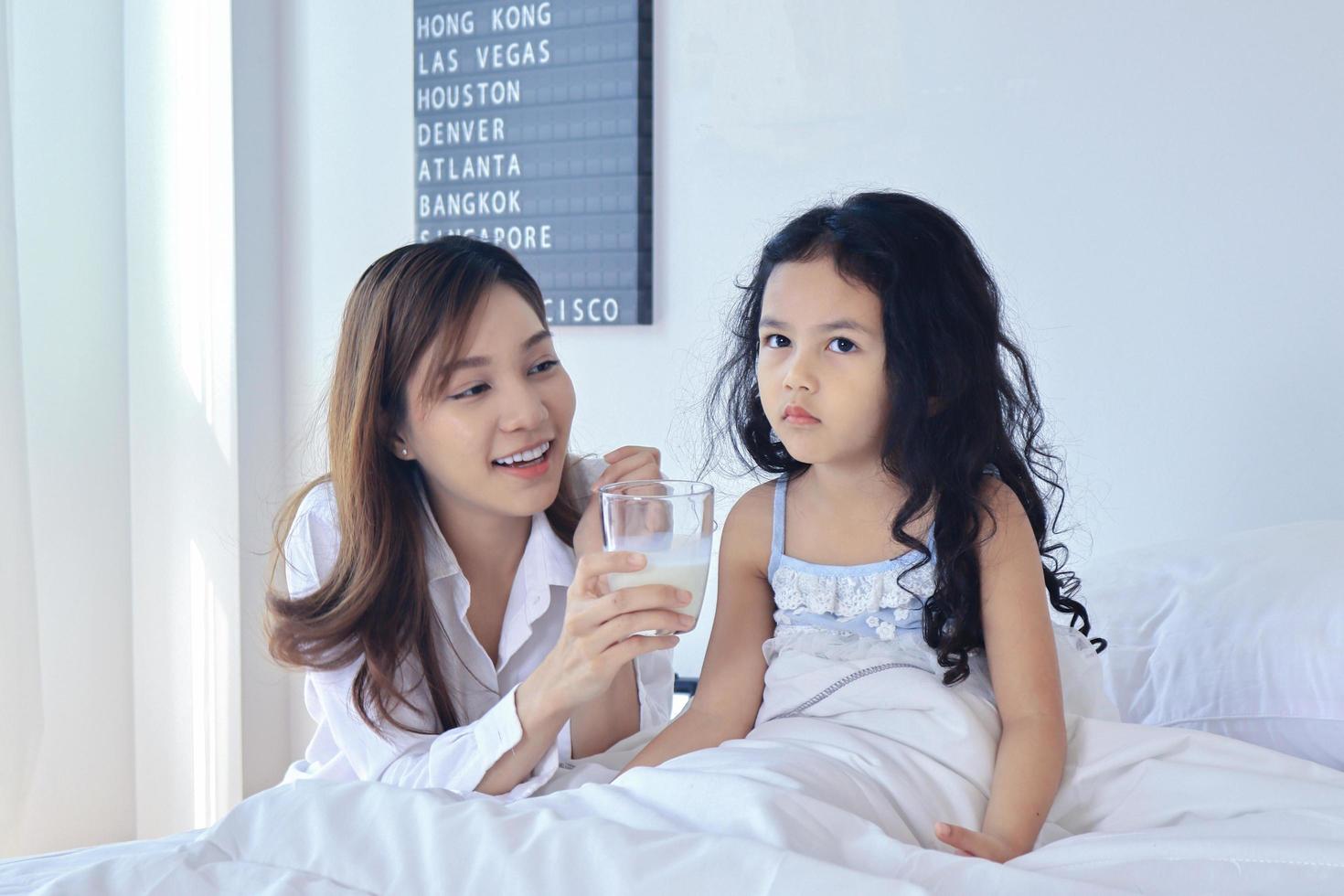 Mother is giving her daughter milk in the morning photo