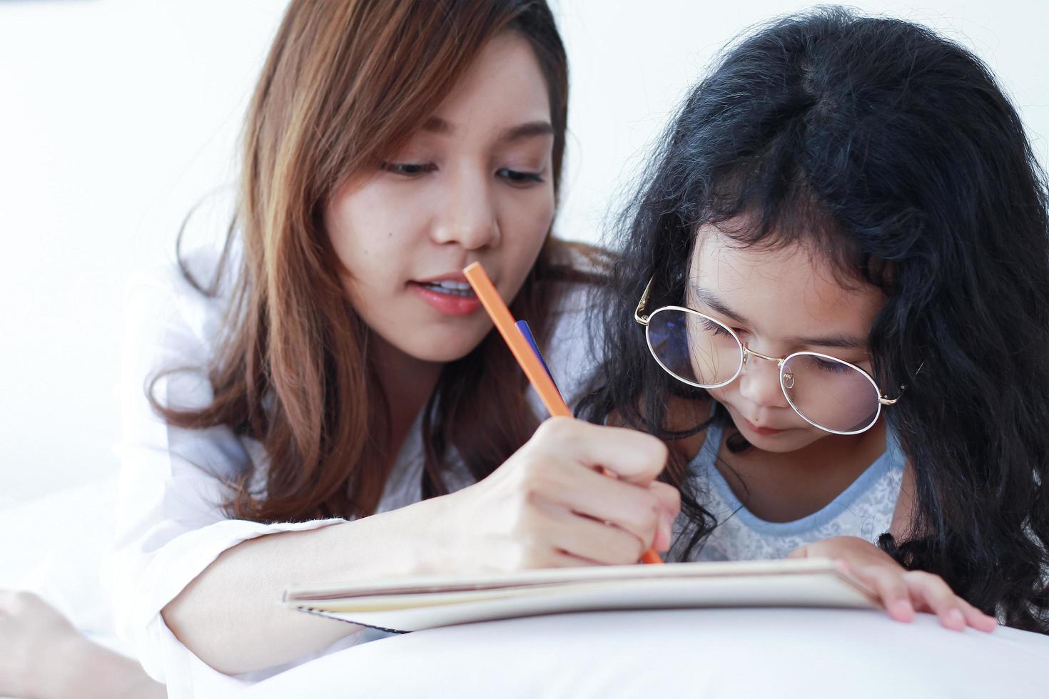 Asian mother is teaching her daughter homework at home photo
