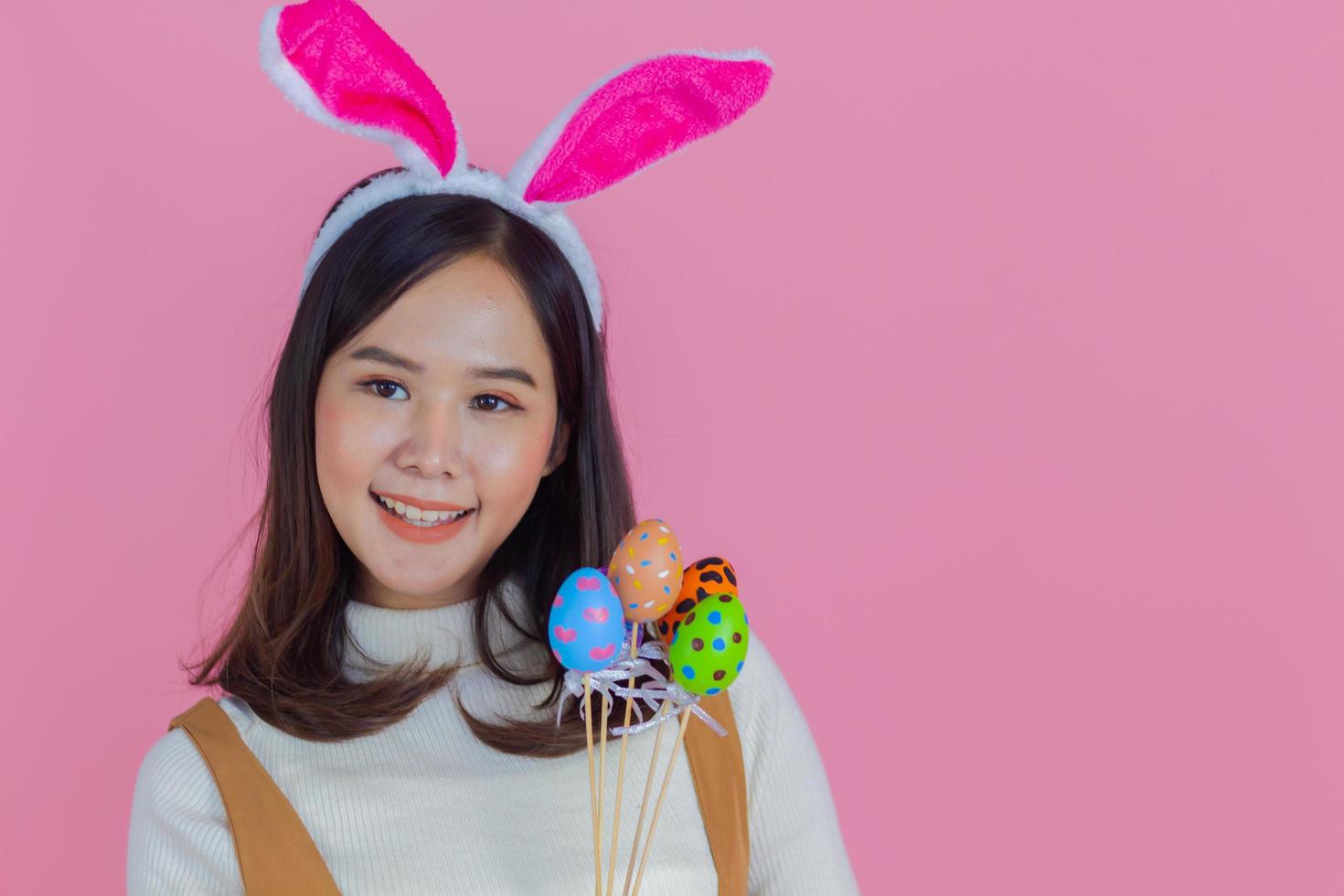 Portrait of beautiful Asian girl with an Easter egg on a pink background copy space photo