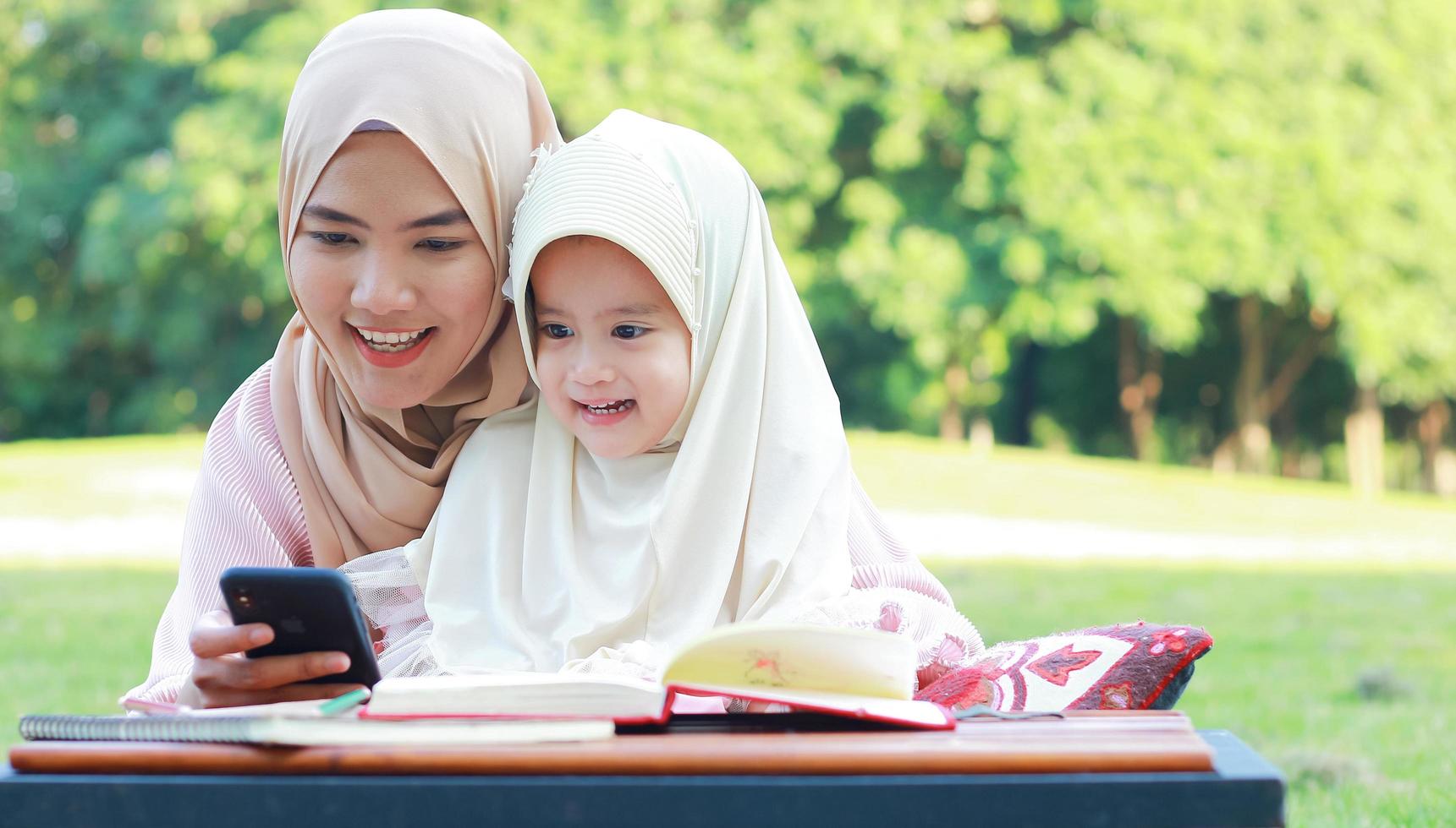 Muslim mother and daughter enjoying their holiday in the park photo