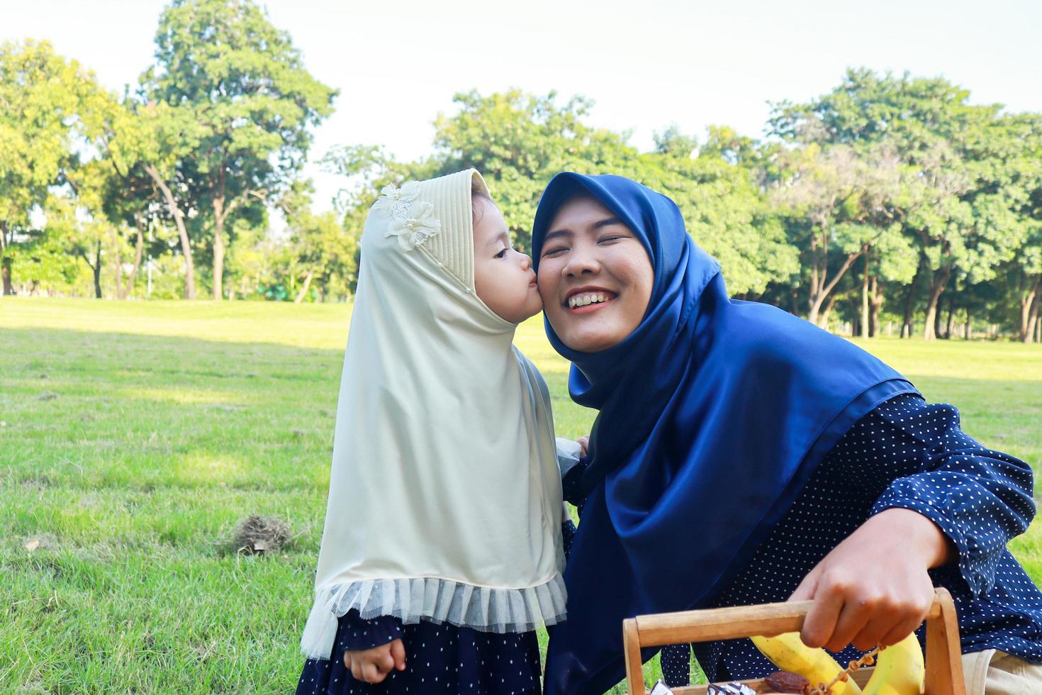 Muslim mother and daughter enjoying their holiday in the park photo