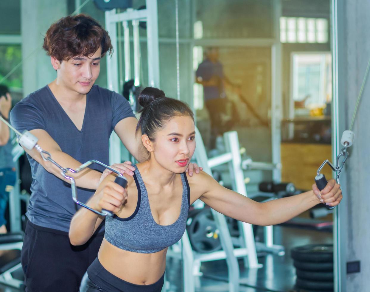 Asian woman is exercising in a gym with a personal trainer photo