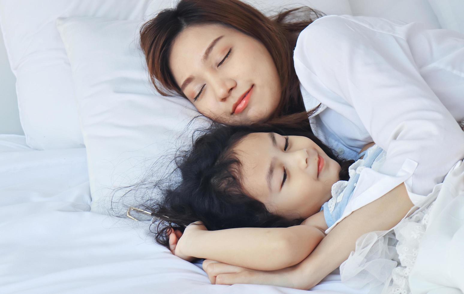 Mother cuddling her daughter in bed lovingly photo