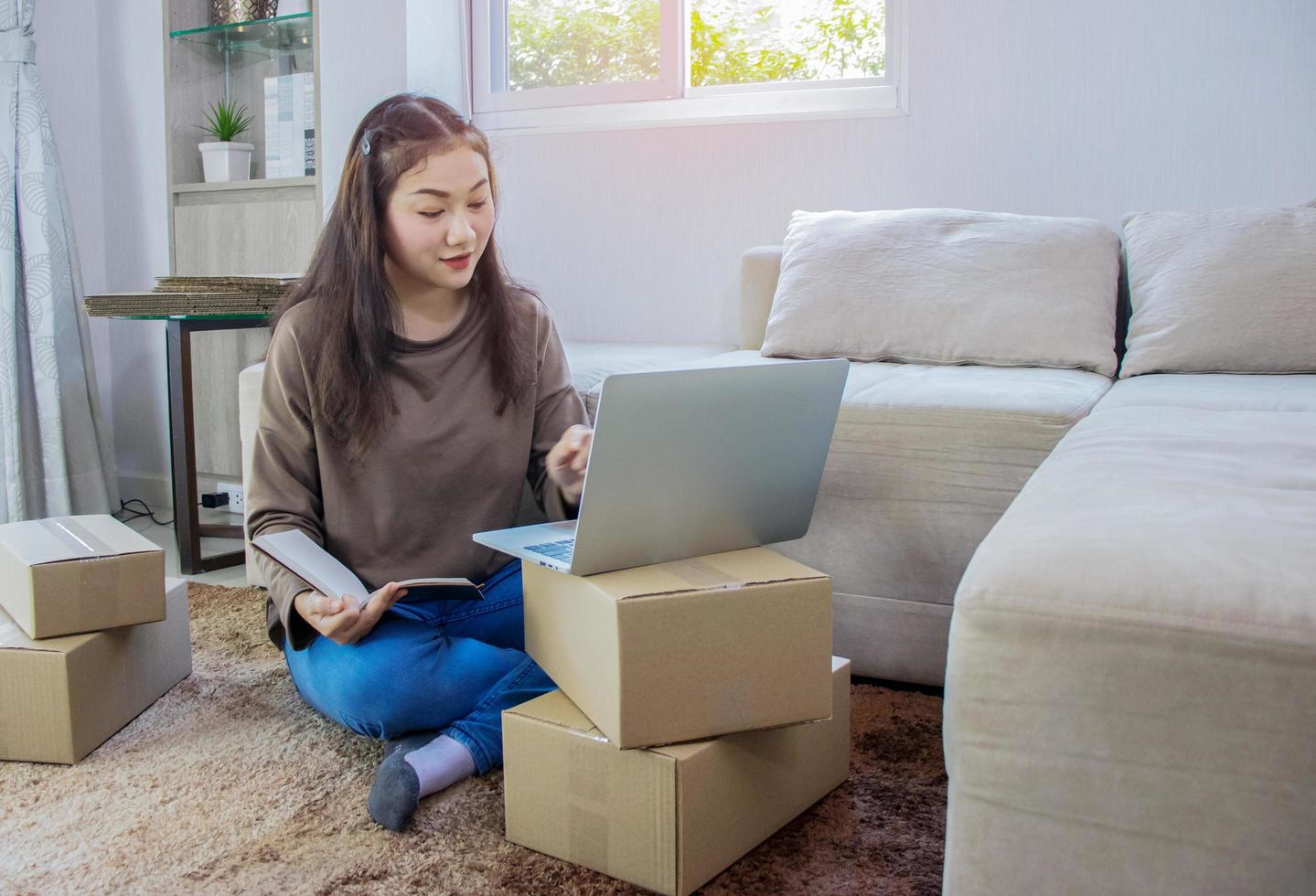 Beautiful Asian woman sitting at home and working online, shipping business online photo