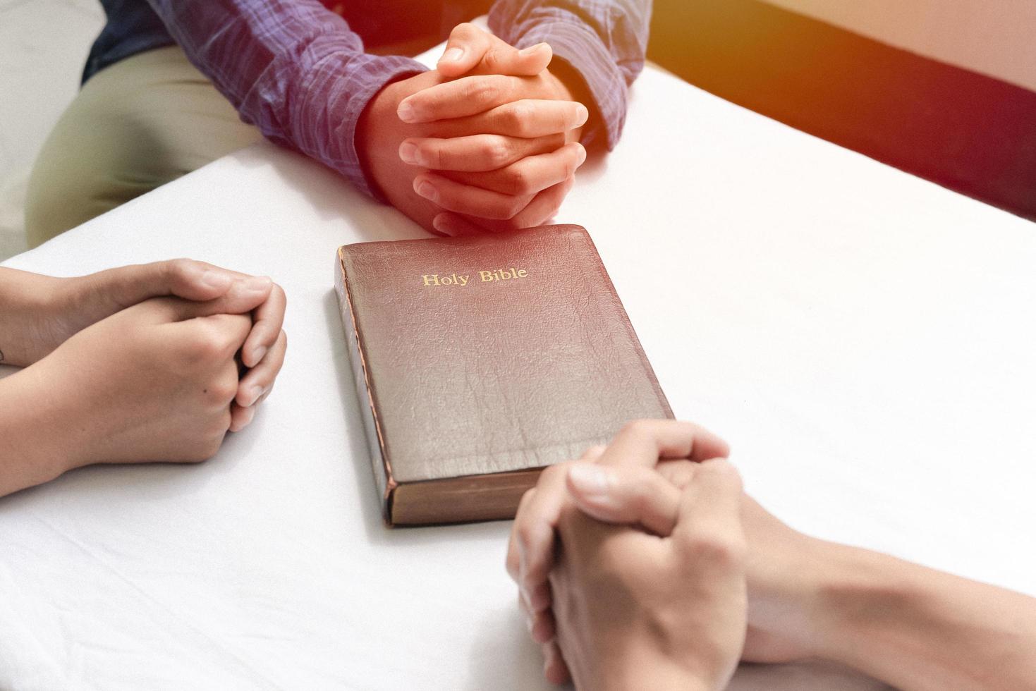 grupo cristiano sentado en una iglesia estudiando la palabra de dios con una biblia en el medio foto