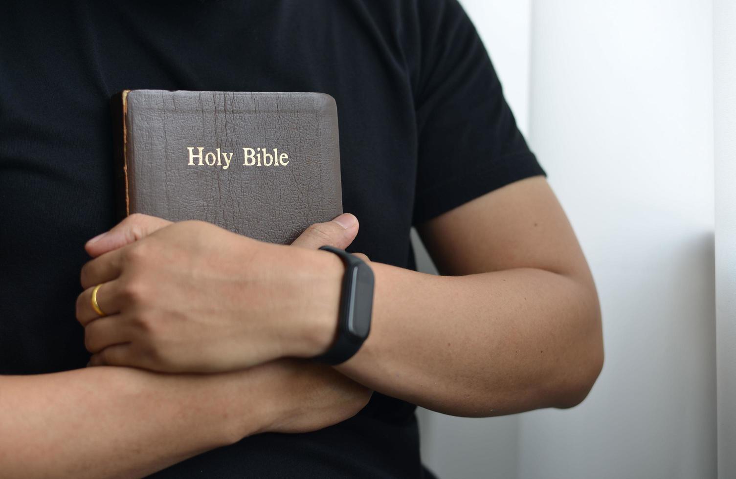 A man is holding and hugging a bible in the morning photo