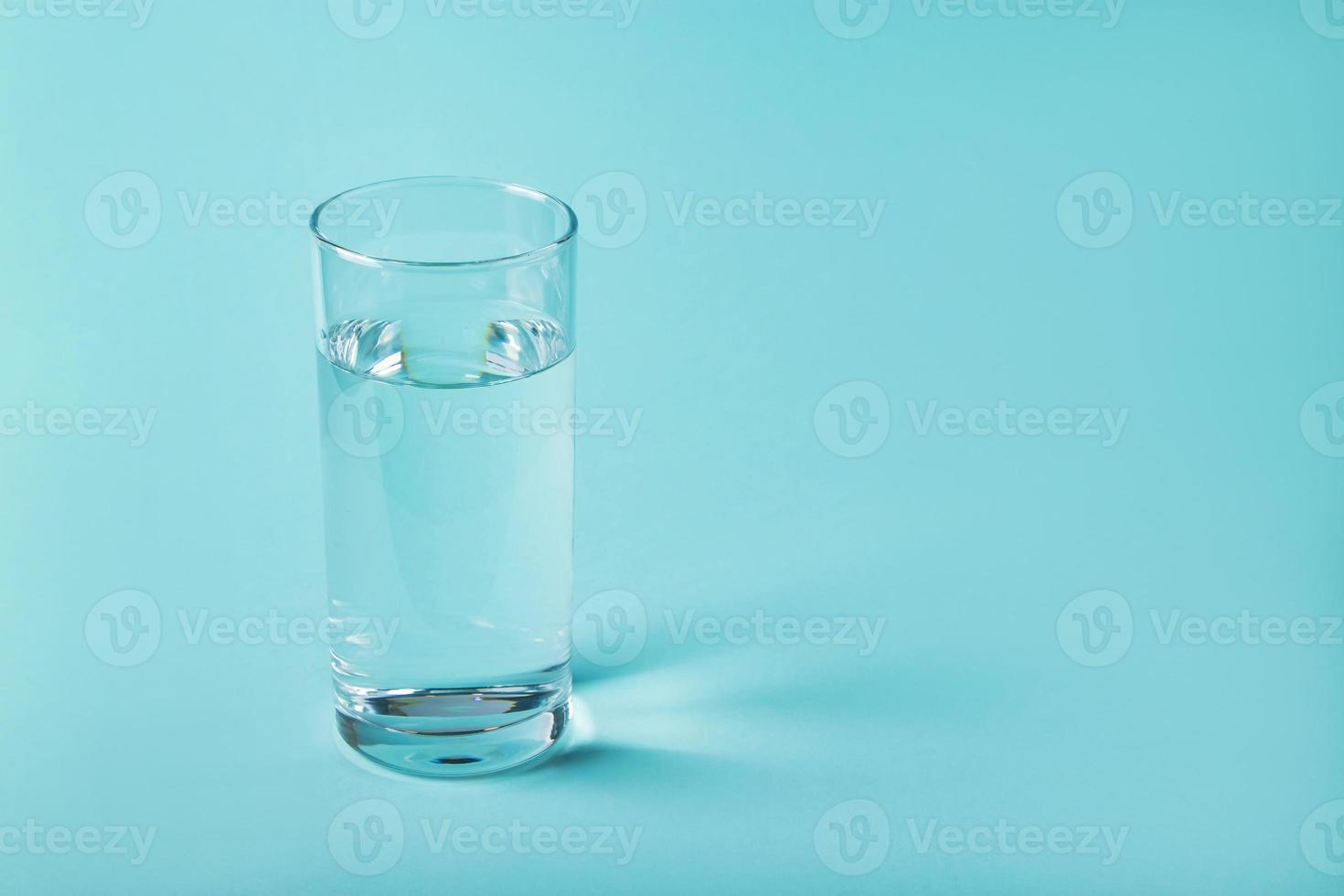 Vaso de agua clara sobre un fondo azul. foto