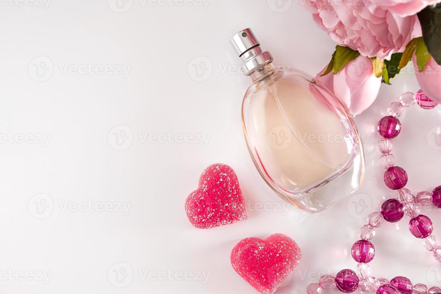 Bottle of perfume flowers and hearts on a light background photo