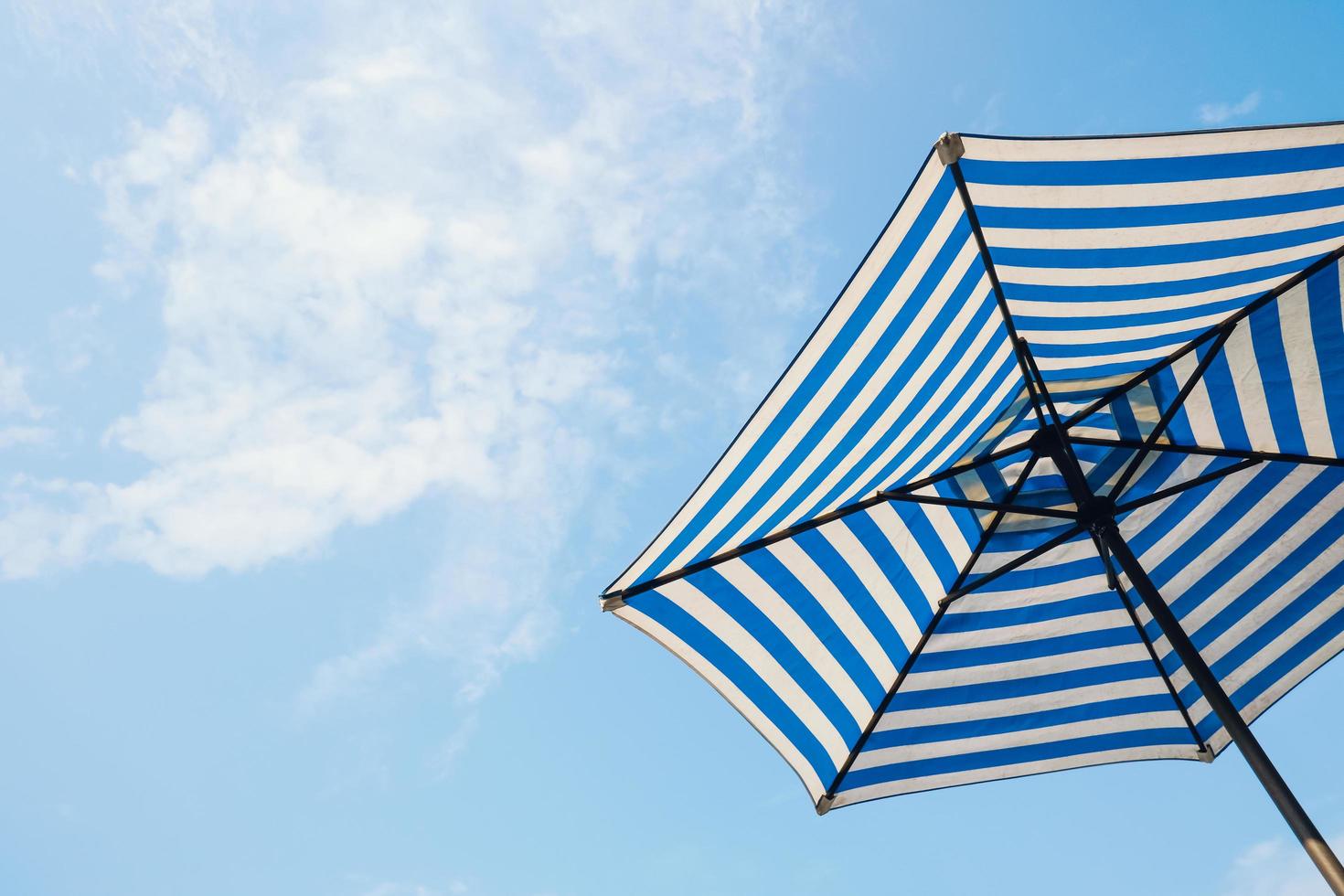 blue striped beach umbrella with sky background photo