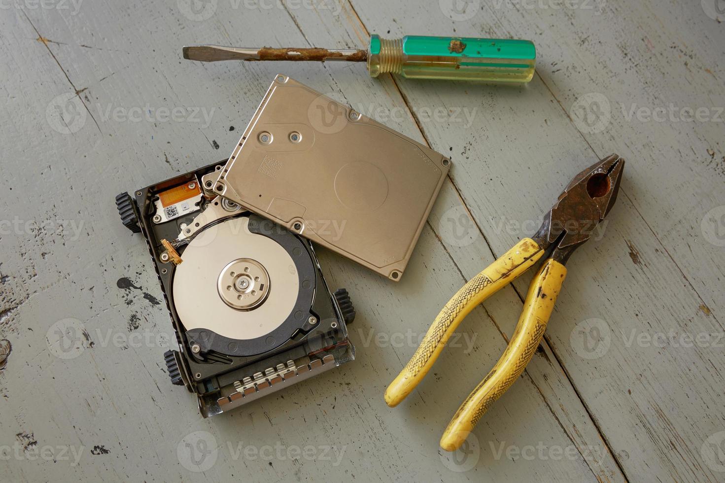 Disco duro roto y destruido y herramientas sobre mesa de madera foto