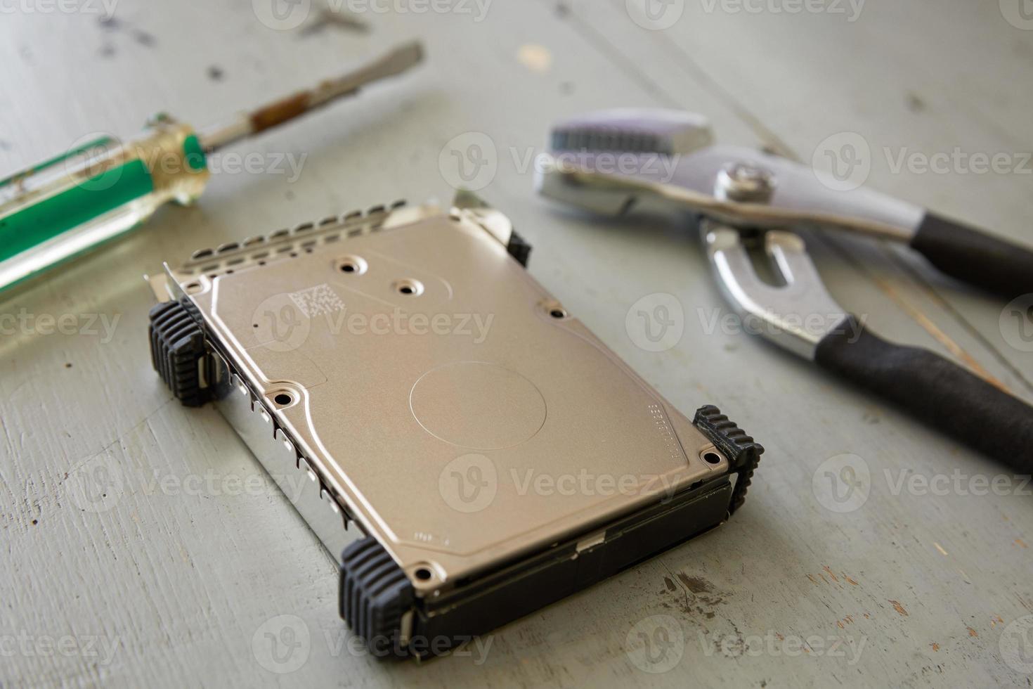 Broken and Destroyed Hard Drive Disk and Tools on Wooden Table photo