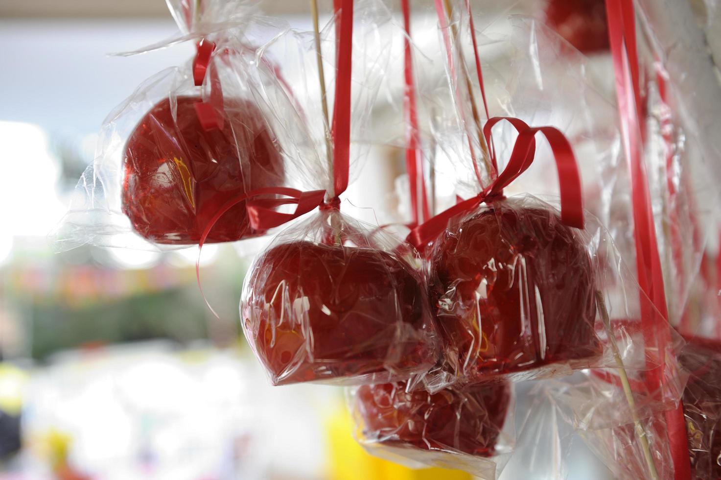 Lots of appetizing red candied apples hanging outdoors photo