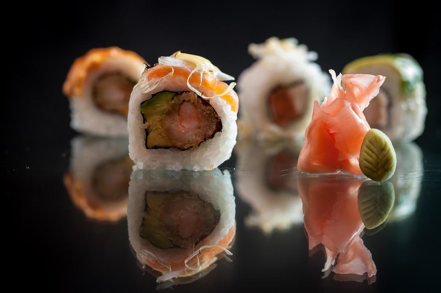 trozos de sushi sobre fondo negro con su reflejo foto