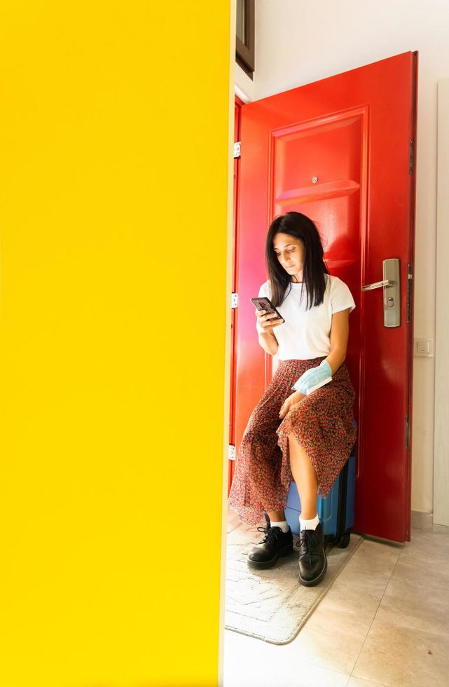 Girl standing by the door with phone and luggage photo