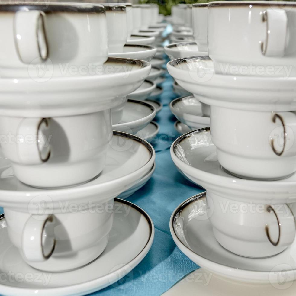 Tazas de café con leche con platos de pie apilados en una fila foto