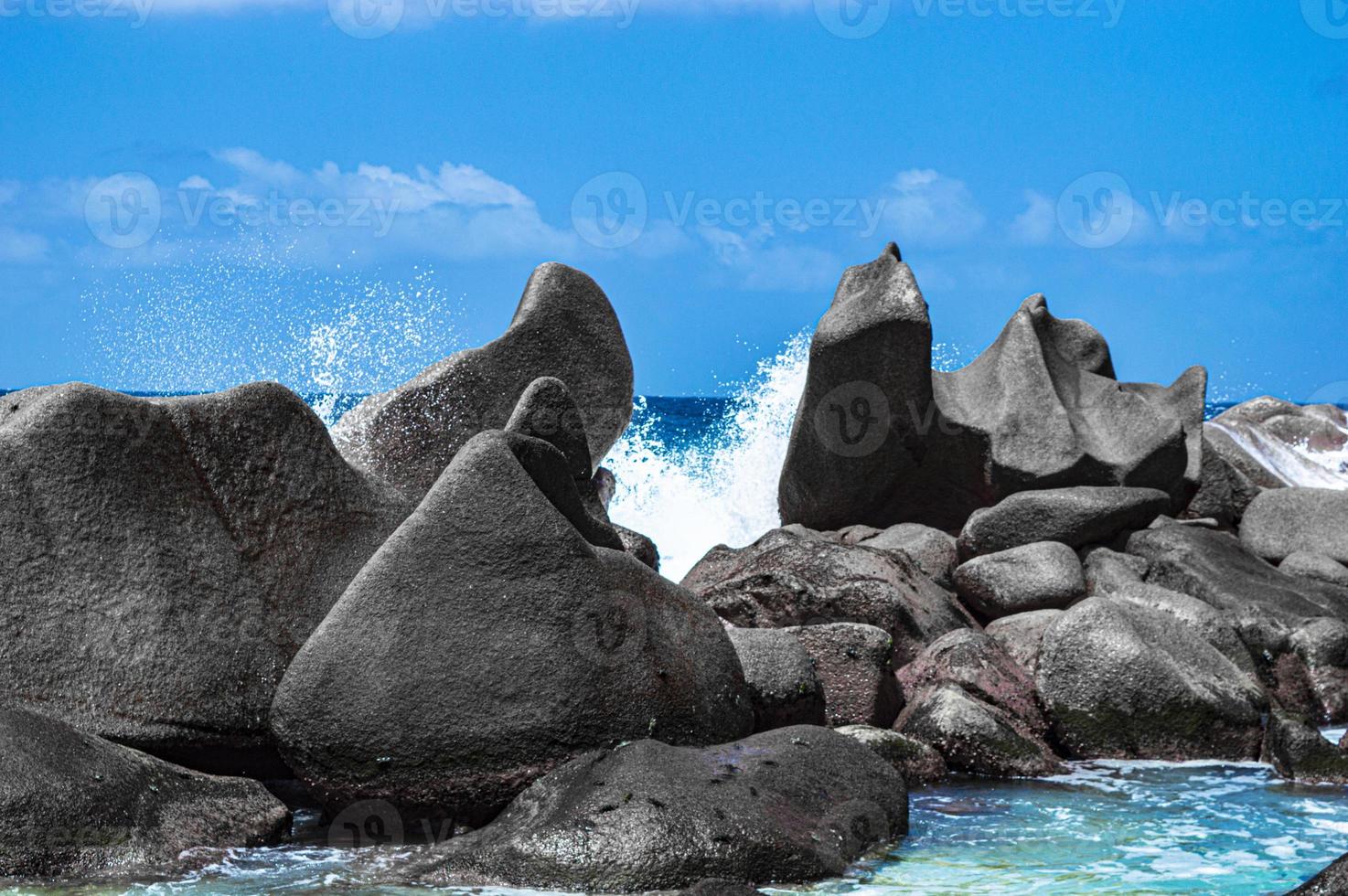 Waves break on secular granite blocks photo