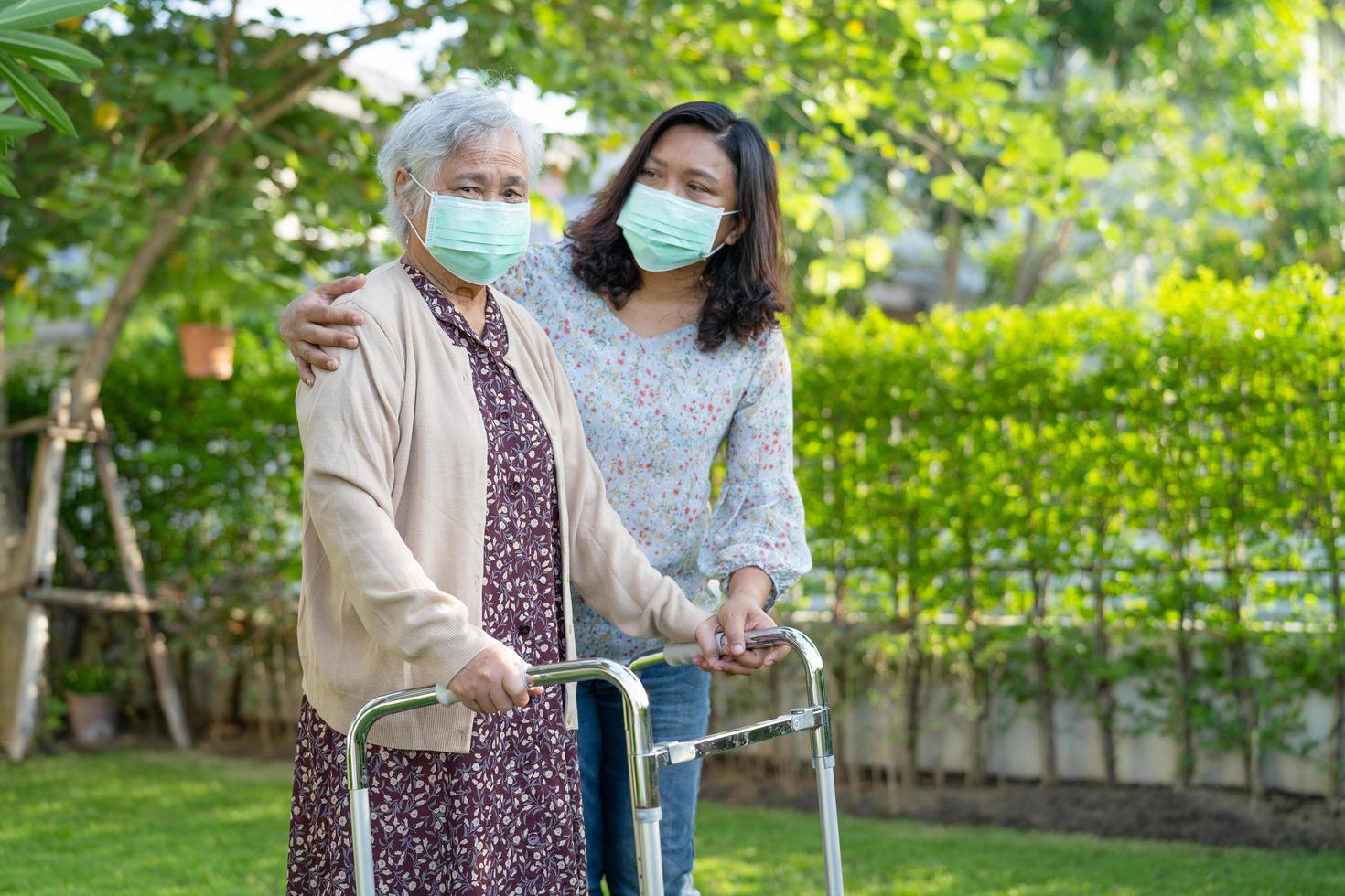 anciana asiática mayor o anciana camina con andador y usa una mascarilla para proteger la seguridad infección covid 19 coronavirus foto