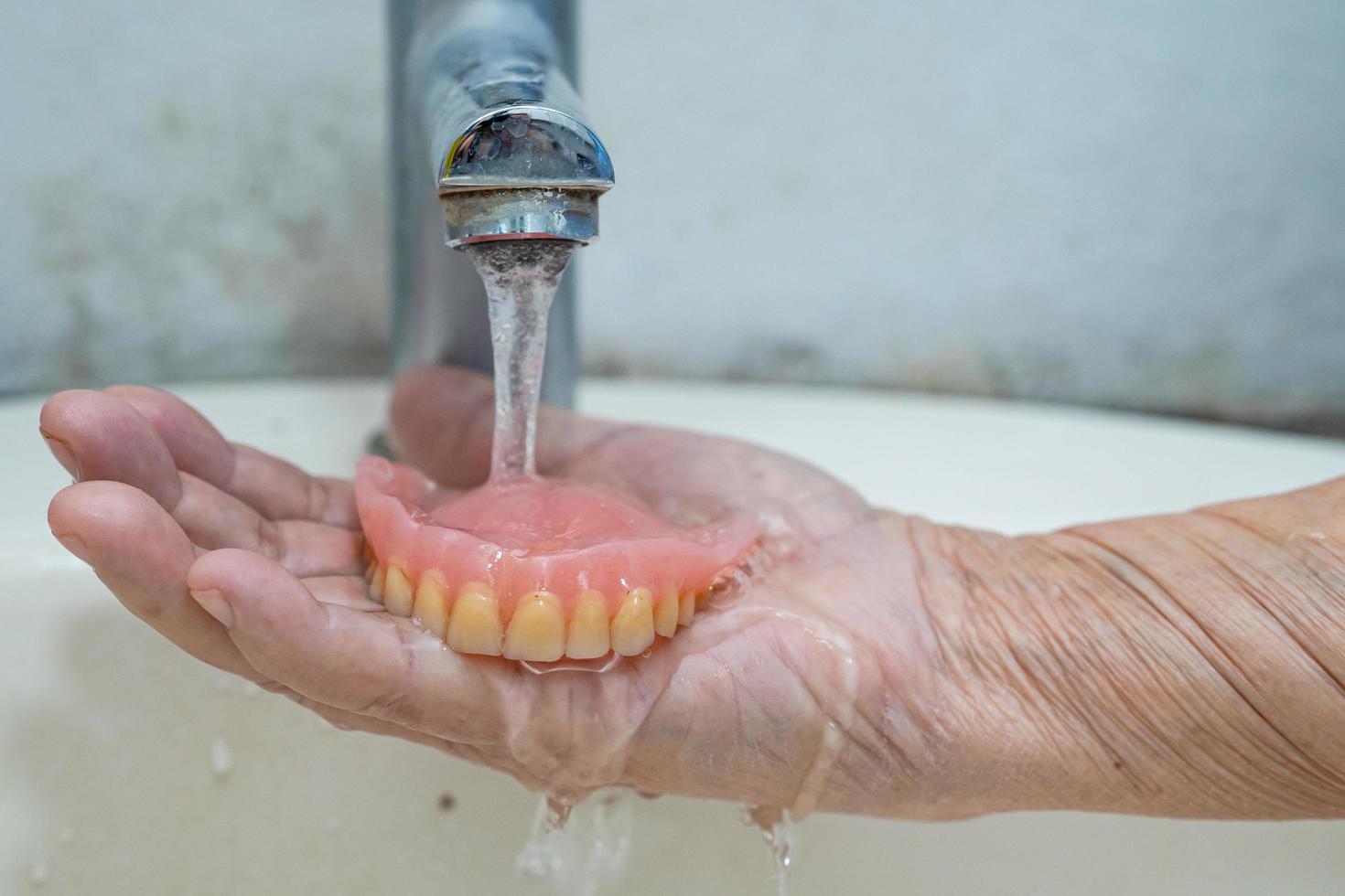 Asian senior or elderly old woman patient holding partial denture of replacement teeth photo