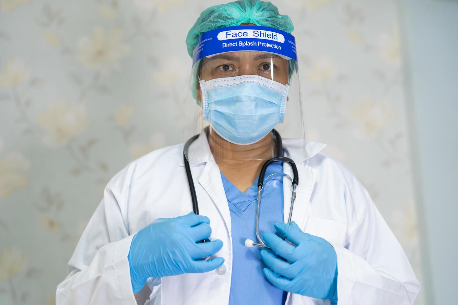 Asian doctor wearing face shield and PPE suit new normal to check patient protect safety infection Covid 19 Coronavirus outbreak at quarantine nursing hospital ward photo