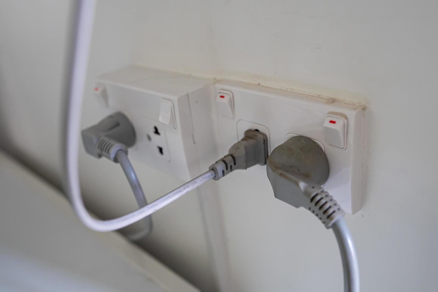 Enchufe eléctrico del cable de alimentación en la pared de la casa foto