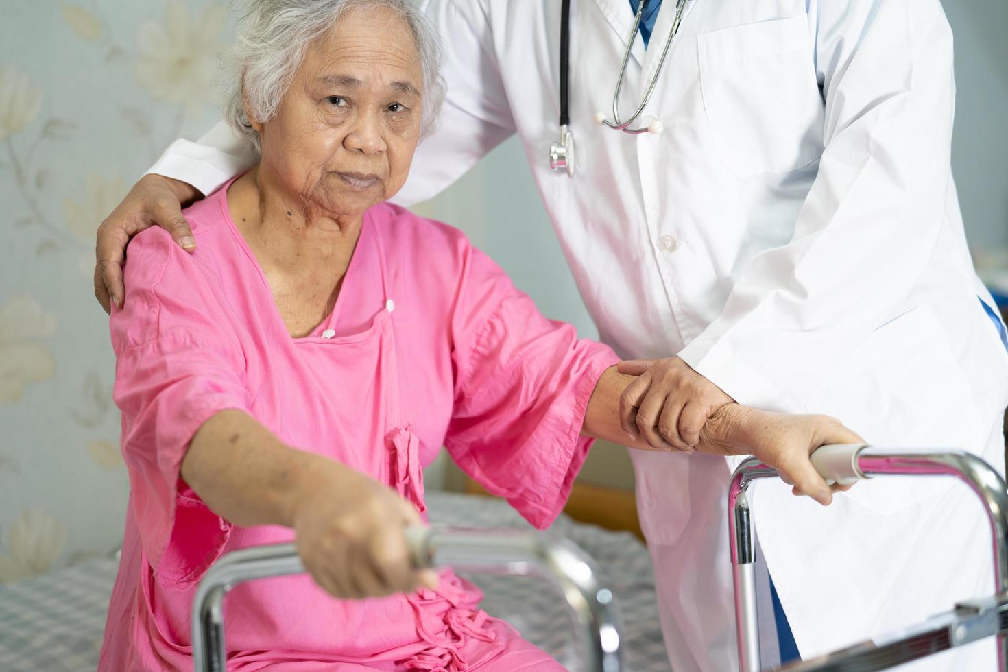 Enfermera asiática fisioterapeuta médico ayudar a anciana asiática paciente con andador foto