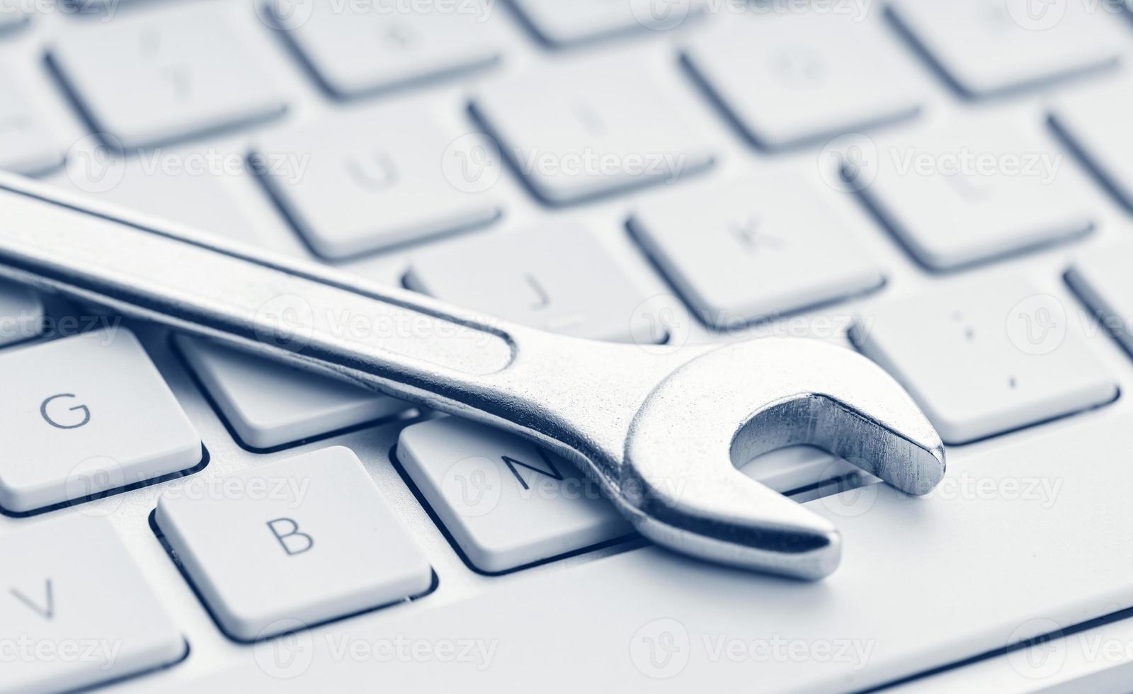 Computer fixing service or maintenance concept background Wrench on computer keyboard photo