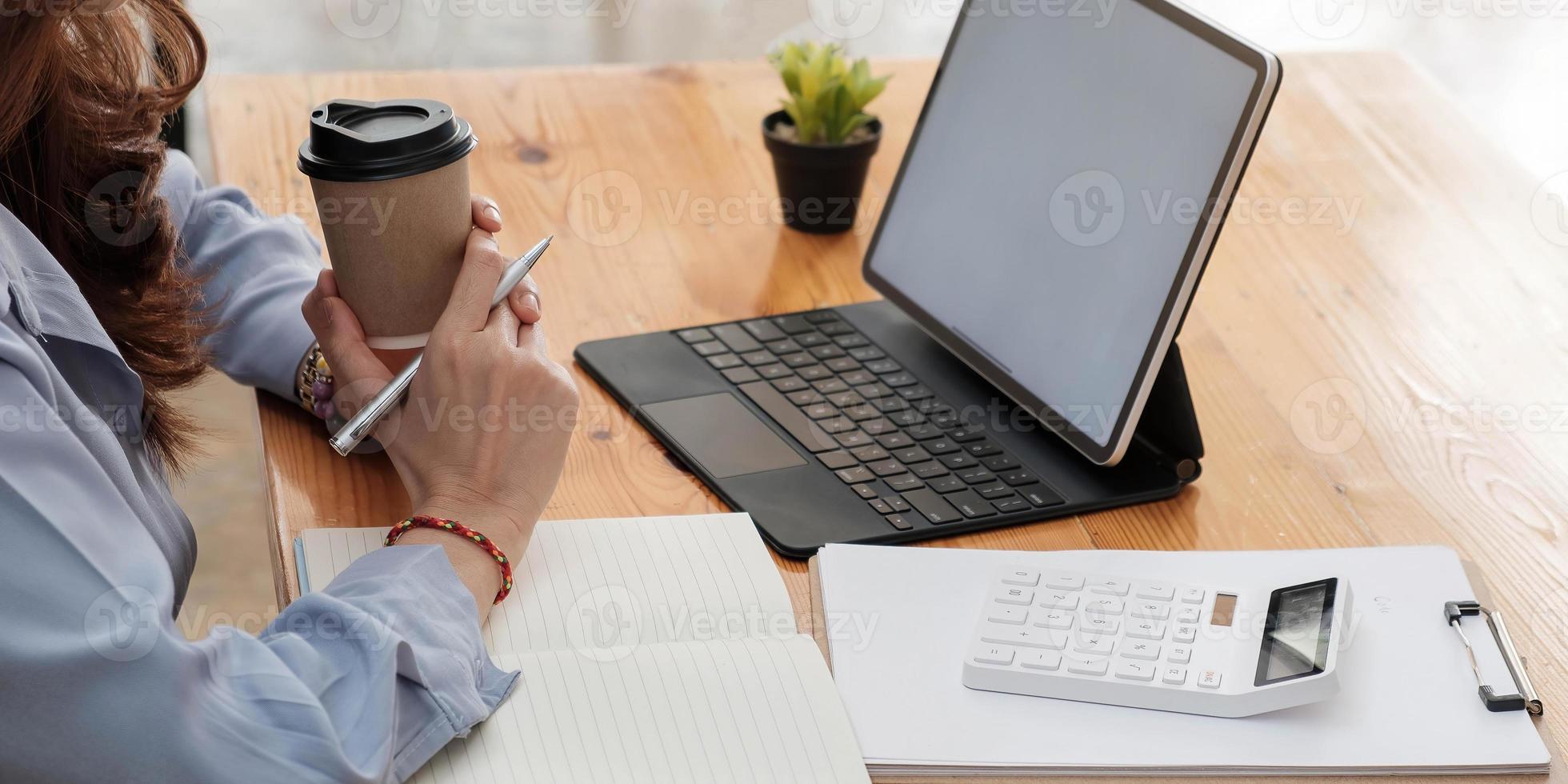 Portrait of businesswoman on workplace with laptop computer and notepad photo