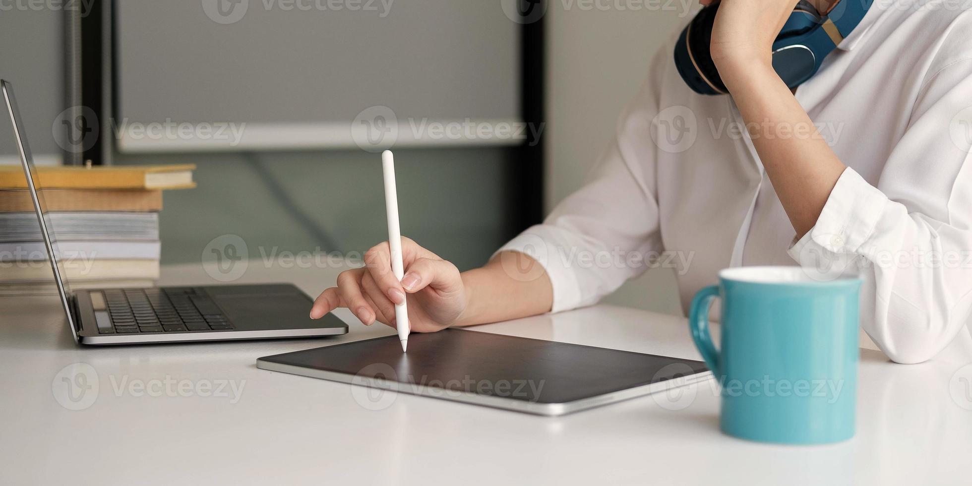 Cerca de una estudiante ocupada estudiando usando la computadora portátil tomar notas en el cuaderno mientras escribe viendo un seminario web o un curso de capacitación en línea en la computadora foto