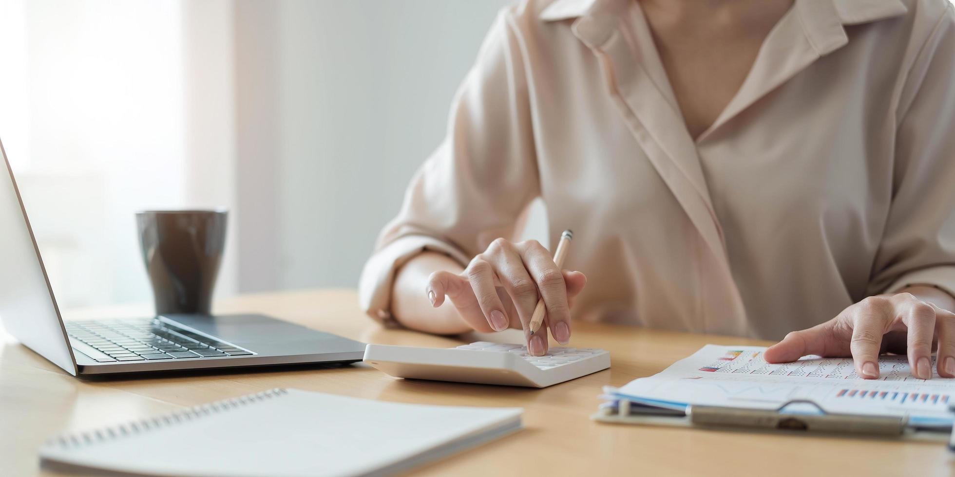 Business woman working in finance and accounting Analyze financial budget with calculator and laptop computer in the office photo