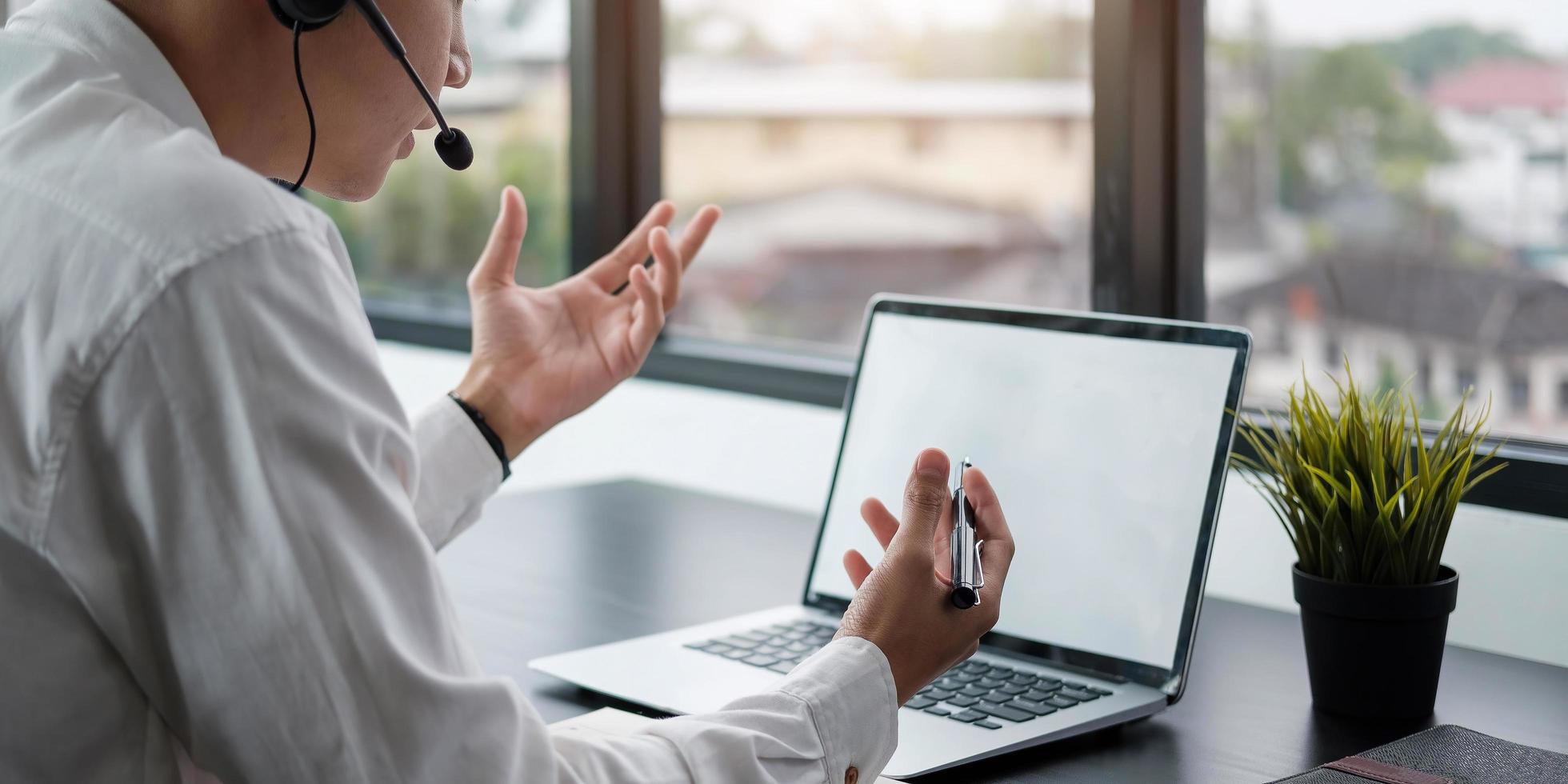 Young man teacher coach wearing headphones speaking holding online lesson Focused student looking at computer monitor screen photo