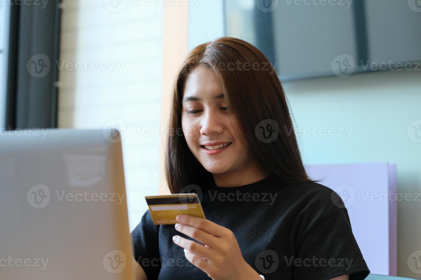 Mujer joven con tarjeta de crédito y uso de computadora para compras en línea foto