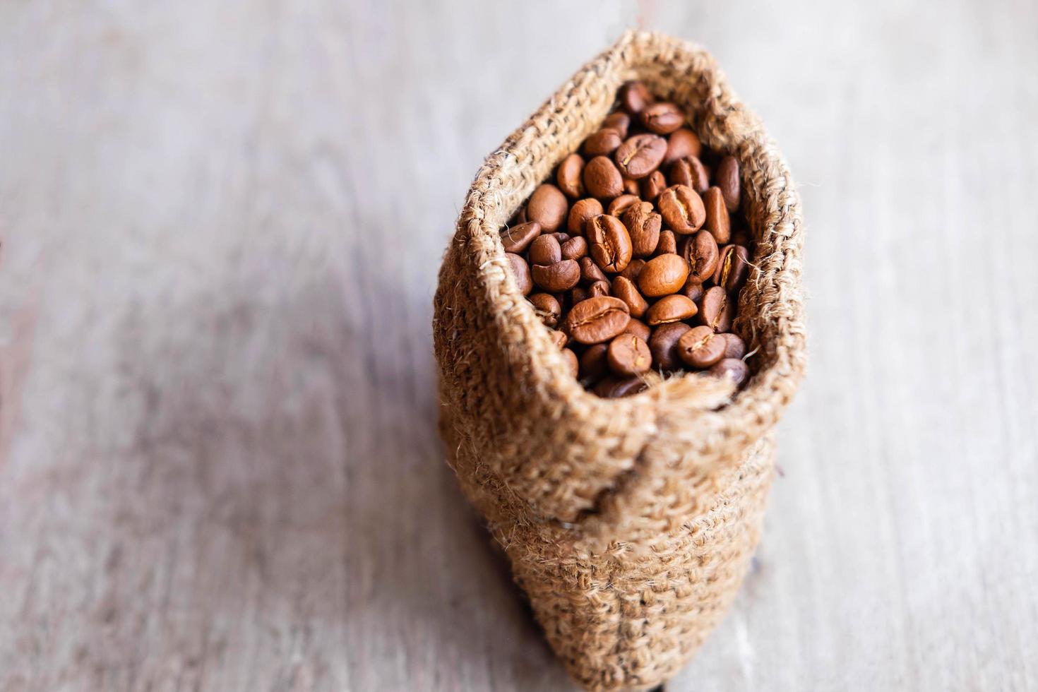 granos de café tostados en una bolsa de saco marrón foto