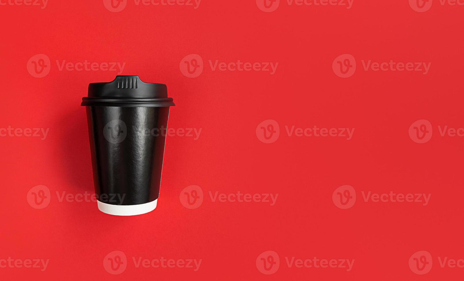 Black paper coffee cup to go on red background with copy space photo