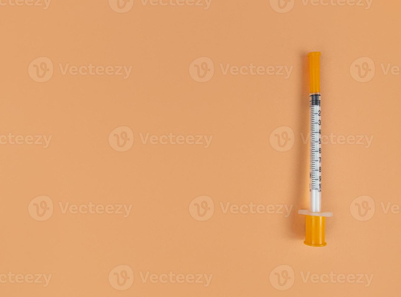 Insulin syringe on orange background with copy space photo
