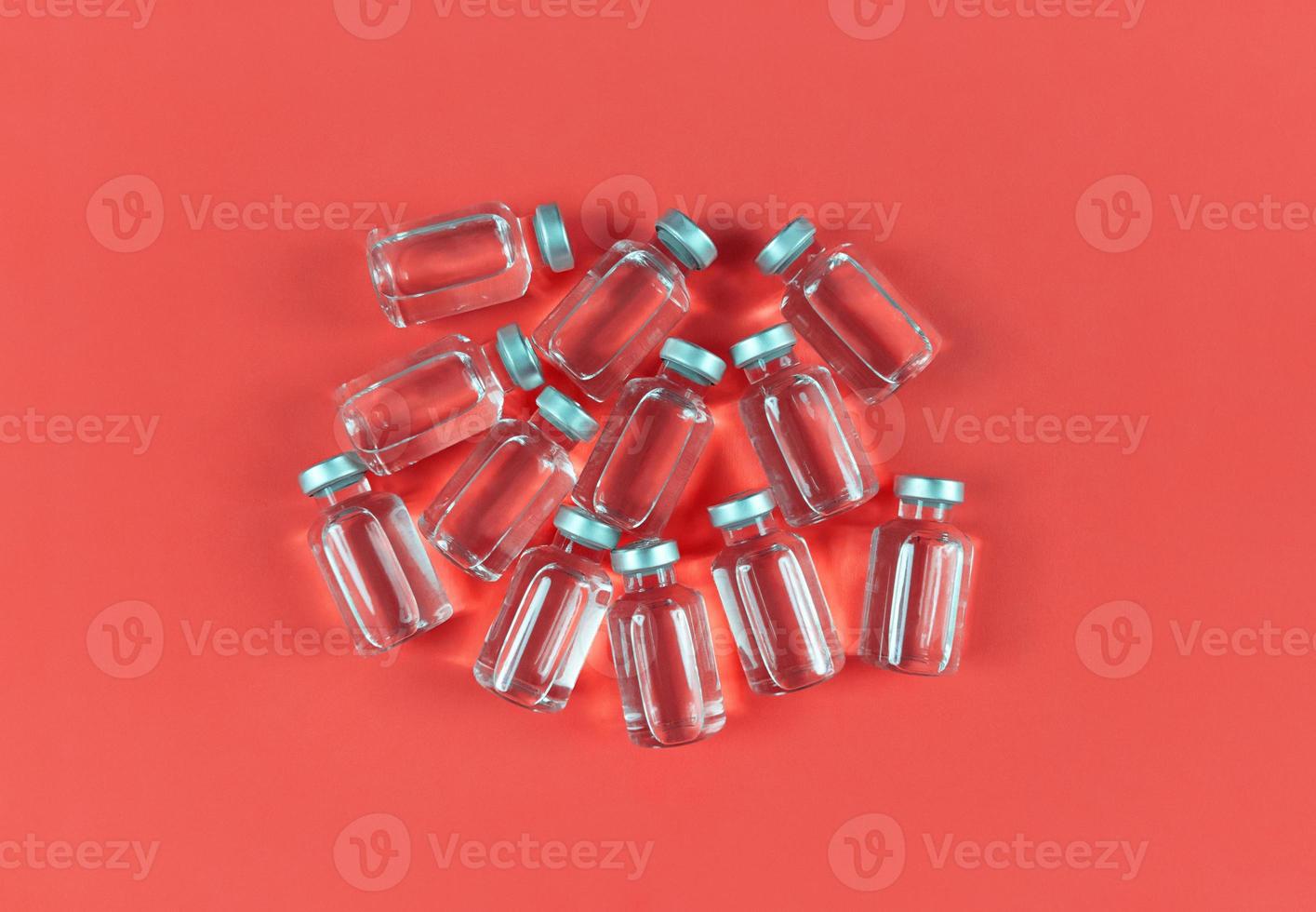 Lots of vials with liquid medicine on red backdrop photo