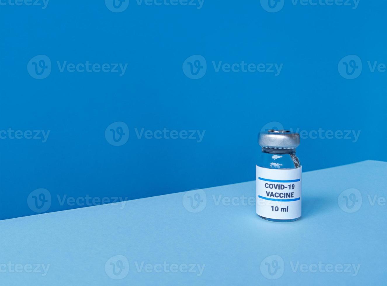 Medicine bottle with covid 19 vaccine on blue backdrop with tilted trendy skyline and copy space photo