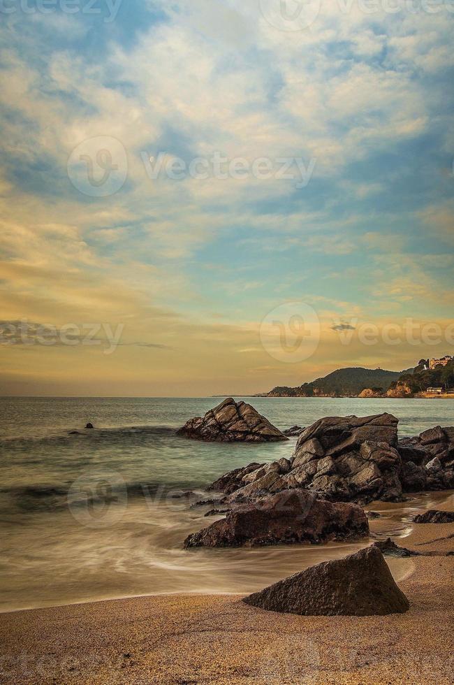 Bonita playa rocosa al atardecer en Cataluña foto